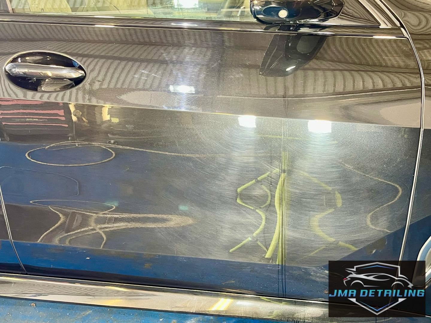 Dark vehicle door with heavy swirl marks before paint correction